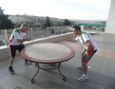 Josu Rubio y David Alonso simulando un partido de tenis de mesa en una de las mesas de la terraza