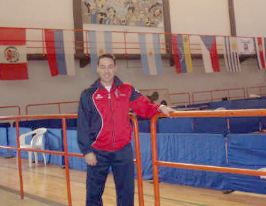 David Alonso, posando apoyado en una barandilla dentro del pabellón, con las banderas de los países al fondo. 